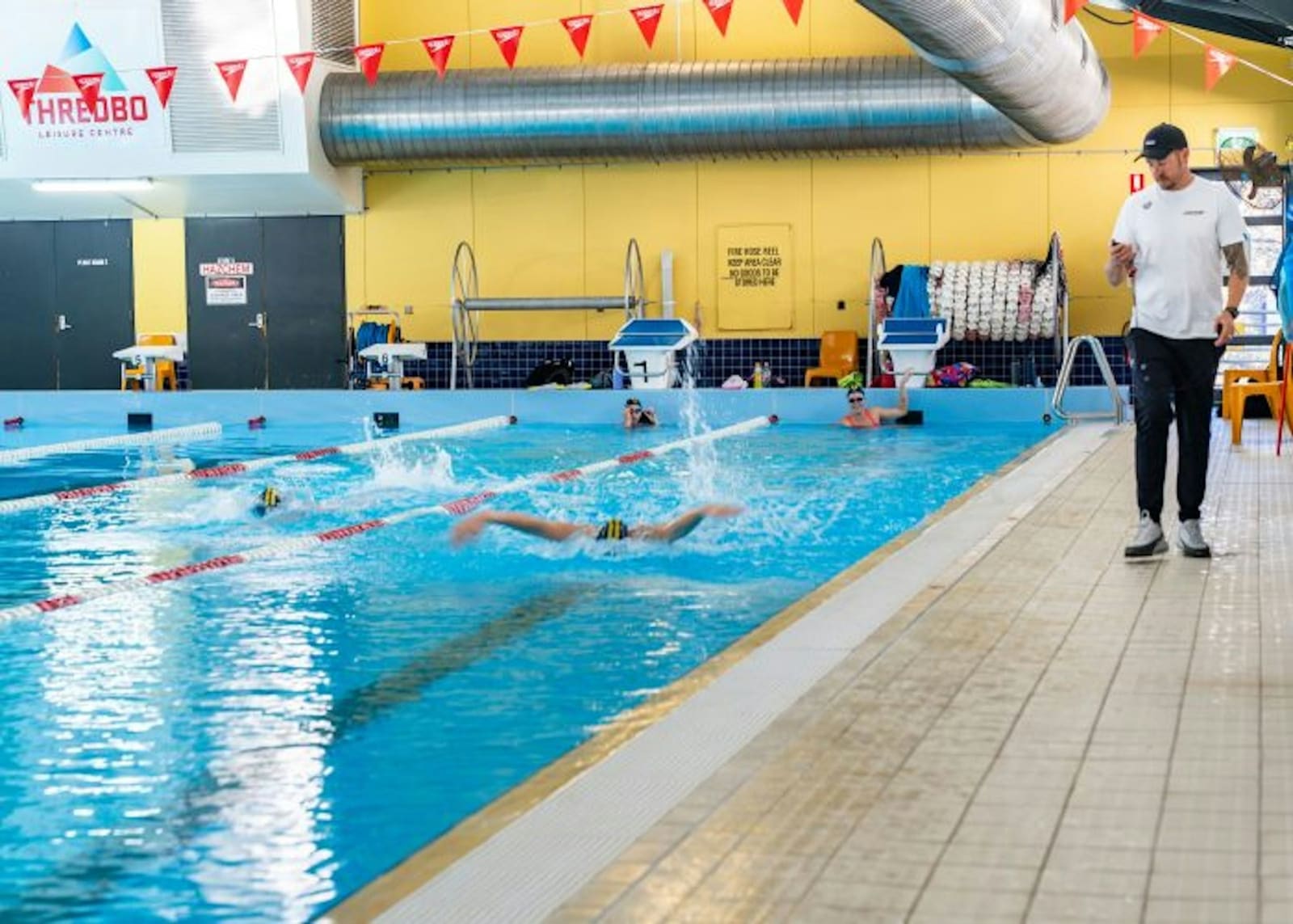 Swimmers doing laps in a bright indoor pool