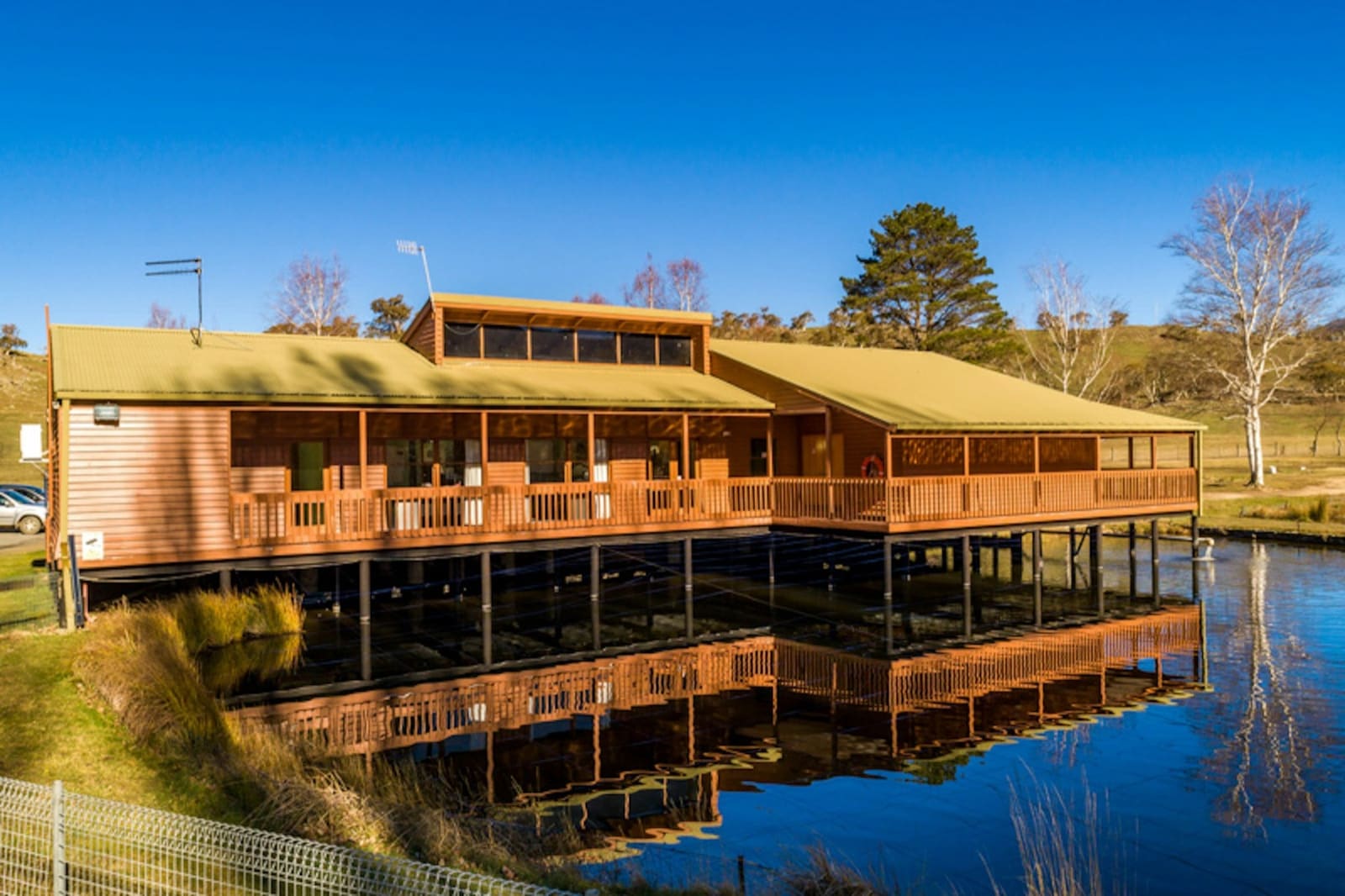 Timber hatchery building on stilts reflected in a still pond